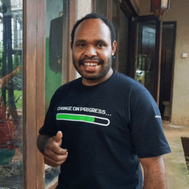 Indonesian male smiles at the camera and gives a thumbs up